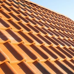 Overlapping rows of yellow ceramic roofing tiles covering residential building roof